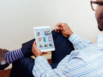 Ein Digital Business Manager sitzt auf dem Boden und schaut auf ein Tablet.