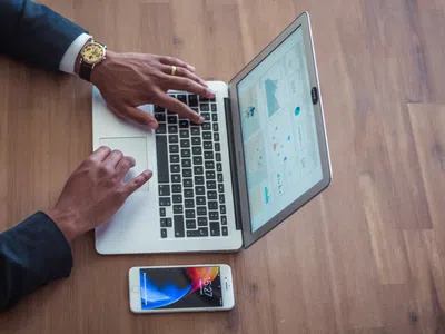 Ein Experte für Business Intelligence mit einem Laptop auf einem Holztisch.