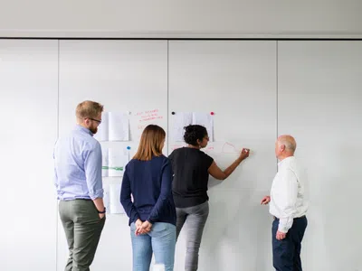 Eine Gruppe von Geprüften Technischen Betriebswirten (IHK) steht an einer weißen Tafel.