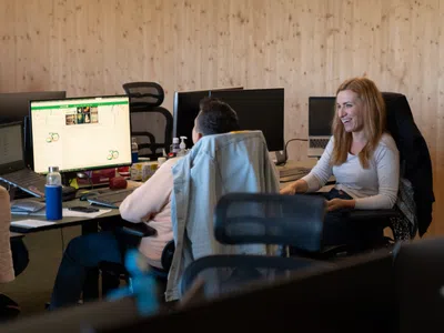 Zwei Studierende sitzen vor einem Computer-Bildschirm und unterhalten sich