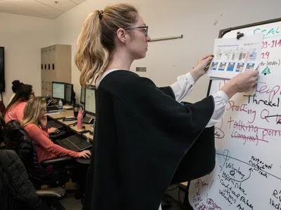 Studentin hängt ein Organigramm an ein Whiteboard