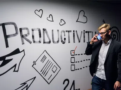 Prozessmanager:in nutzt digitale Methoden und telefoniert vor einer Wand.