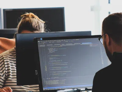 Ein Softwareentwickler und ein Kollege analysieren Daten auf einem Computerbildschirm.