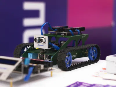 Ein kleiner Roboter mit vier Rädern fährt auf einem Tisch