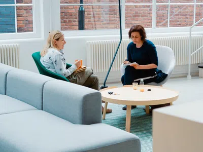 Zwei Studentinnen sitzen in einem Aufenthaltsraum und unterhalten sich