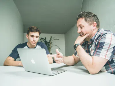 Zwei Technische Einkäufer:innen überprüfen Spezifikationen auf einem Laptop an einem Tisch.