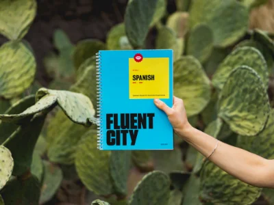 Eine Frau hält ein Spanischbuch in der Hand vor Kakteen