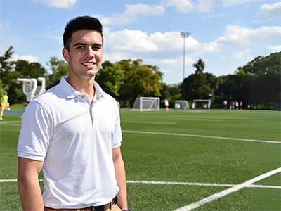 Ein Sportmanagement-Student steht auf einem Sportplatz.  