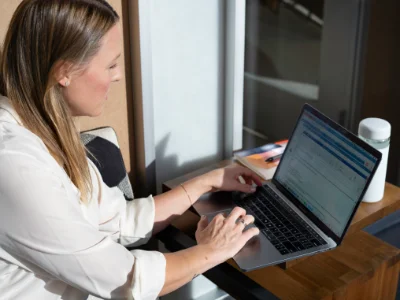 Eine Frau macht das Sprachdiplom Cambridge English am Laptop auf dem Balkon