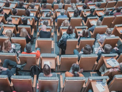 Blick auf einen Hörsaal von oben in dem Studierende einer Vorlesung folgen